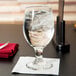 A Libbey banquet goblet filled with ice water on a table with a napkin