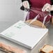 A woman in a white apron and gloves wrapping a sandwich in LK Packaging clear plastic.