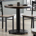A Lancaster Table & Seating counter height table base column and rod on a table with two chairs.
