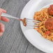 A Oneida Baguette European table fork in a plate of spaghetti and meatballs.