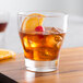 An Arcoroc Urbane double old fashioned glass with a drink and ice cubes and a slice of orange.