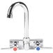 A chrome Advance Tabco wall mount faucet with blade handles and a gooseneck spout.