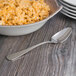 A bowl of macaroni and cheese with a Oneida Baguette stainless steel serving spoon on a table.