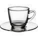 An Acopa clear glass coffee cup on a saucer.