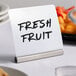 A stainless steel American Metalcraft table card holder with a sign on a plate of fruit.