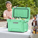 A woman opening a CaterGator Seafoam cooler with drinks.