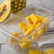 A Carlisle clear plastic food pan drain tray filled with pineapple and other fruit.