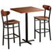 A Lancaster Table & Seating bar height table with two chairs and a wooden seat.