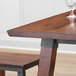 A Lancaster Table & Seating wooden live edge bar height table with a glass on it.