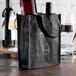A black LK Packaging reusable bag holding two wine bottles.