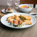 A Blue Jade Thunder Group melamine serving platter on a table with sushi and other food.