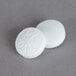 A close-up of two white Medi-First aspirin tablets.
