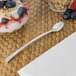 A Fineline silver plastic cocktail spoon next to a bowl of yogurt with berries.
