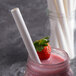 A strawberry in a glass jar with a EcoChoice white paper straw.