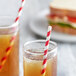 Two glasses of red liquid with EcoChoice red striped paper straws and a sandwich.