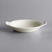 A white porcelain shirred egg dish with handles.