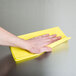 A hand using a yellow Chicopee Masslinn dusting cloth.