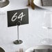 A table setting with a place card in a Choice chrome menu / card holder on a table in a fine dining restaurant.