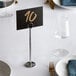 A table setting with a Choice 10" chrome table number holder and a place card.