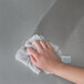 A hand using a white towel to clean stainless steel.