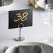 A white table with a Choice Chrome Menu / Card Holder with a brown stripe.