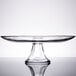A clear glass Anchor Hocking tiered cake stand on a reflective surface.
