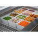 A Tablecraft brushed aluminum cold well drop-in template filled with food on a counter.
