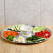 An 18" foil 7 compartment lazy susan tray with a container of vegetables on it.