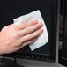 A hand using a Weiman E-Tronic Electronics Cleaning Wipe to clean a screen.
