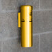 A gold cylinder with Aarco SC15W Cigarette / Ash Receptacle on a brick wall.