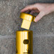 A hand putting a cigarette in a gold wall mounted ash receptacle.