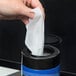 A hand removing a Weiman E-Tronic Electronics Cleaning wipe from a blue and white container.