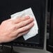 A hand using a Weiman E-Tronic Electronics Cleaning Wipe to clean a screen.