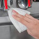 A hand using a Weiman stainless steel cleaning wipe to wipe a kitchen sink.