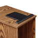 A black tablet on a wooden podium with a medium oak finish.