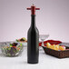 A Chef Specialties Chateau wine bottle salt mill on a table next to a bowl of food.