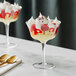 Two Acopa Deco coupe glasses filled with a dessert of whipped cream and strawberries.