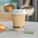 A close-up of an EcoChoice kraft paper coffee cup with a croissant on a table.