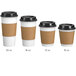 A group of white paper coffee cups with brown sleeves and lids.