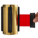 A hand holding a gold CSL stainless steel stanchion head with red tape.