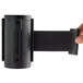 A hand holding a black cylinder with a clip on the end of a black belt.