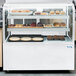An Avantco bottom shelf kit installed in a display case on a bakery counter filled with pastries.