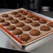 A SILPAT® full-size baking mat on a metal baking sheet with chocolate cookies.