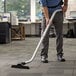 A man using a Lavex aluminum S-wand to vacuum a corporate office cafeteria.