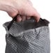A person's hand holding a grey Lavex cloth filter bag for a backpack vacuum.