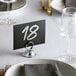 A Choice chrome table card holder with a table number on it on a fine dining table.
