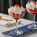 Two Acopa coupe cocktail glasses filled with dessert topped with strawberries and whipped cream.