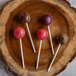 A group of lollipops on a wooden plate with paper lollipop sticks.