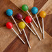 A group of lollipops on paper lollipop sticks on a wood surface.