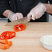A person using a Mercer Culinary Genesis chef knife to slice a bell pepper.